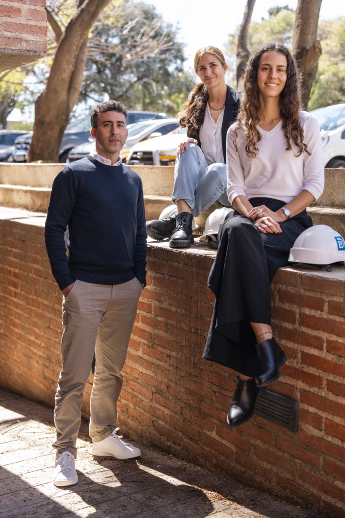 Tres integrantes del equipo Depro con cascos en un patio de ladrillo